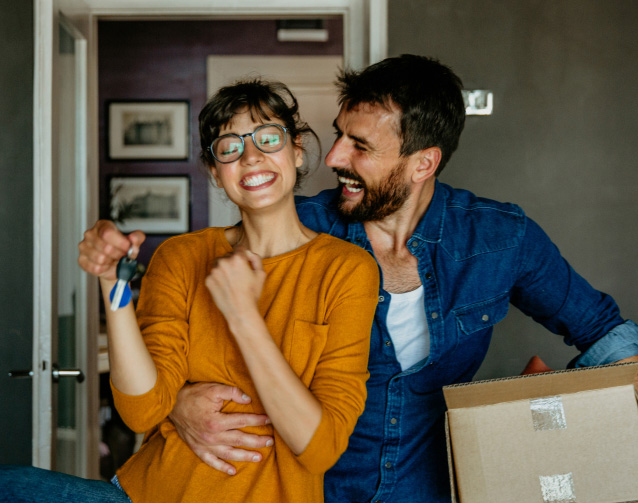 Couple laughing and holding keys to new home
